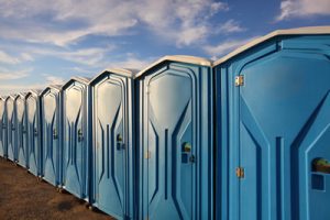 line of porta potties on a dirt patch